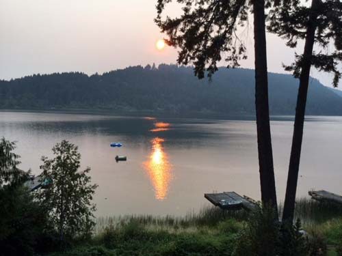 Sunset reflecting on a Salt Spring Island lake, framed by fir trees and docks