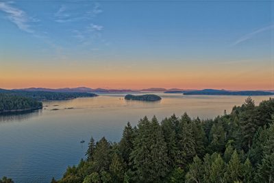 Sunset over the Gulf Islands from a Salt Spring Island hillside, with a sailboat anchored below